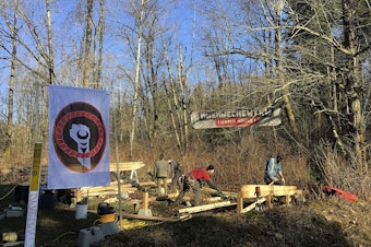 caption: FILE: Anti-pipeline activists build a so-called 'Watch House' near Kinder Morgan's tank farm in Burnaby, British Columbia, Canada, Saturday, March 10, 2018.
