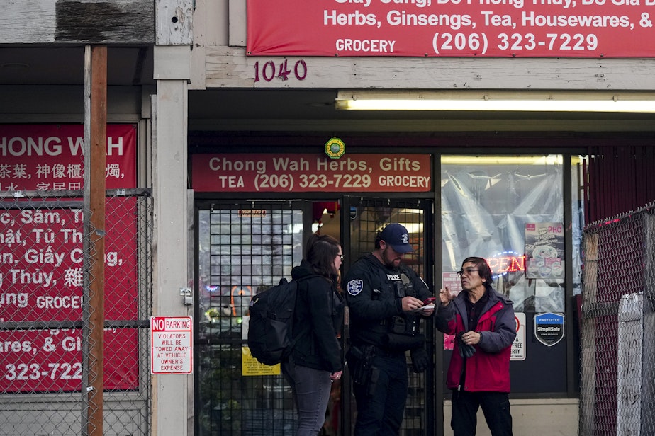 caption: Police officers take a statement from a nearby business owner after multiple people were stabbed Friday, Nov. 8, 2024, in the Chinatown-International District in Seattle.