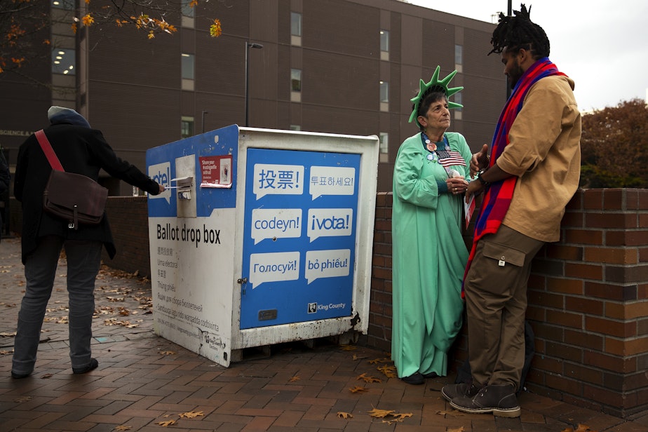 caption: Patti Gorman, dressed as lady liberty, talks with her former Seattle Central student, Afrikaan Sahra, right, as voters cast their ballots on Tuesday, Nov. 5, 2024, outside of Seattle Central College in Capitol Hill. Sahra was voting for the first time after receiving U.S. citizenship.