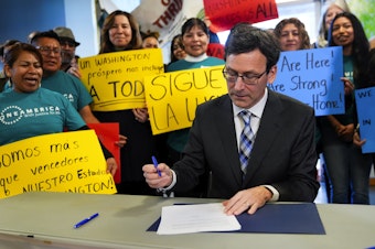caption: Washington Gov. Bob Ferguson signs an executive order creating a family separation rapid response team aimed at responding to the Trump administration's immigration policies, Monday, Jan. 27, 2025, in Seattle.
