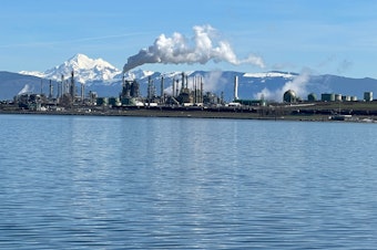caption: Mount Baker looms behind the Marathon Petroleum refinery on Fidalgo Bay in Anacortes, Washington, on Mar. 16, 2024.