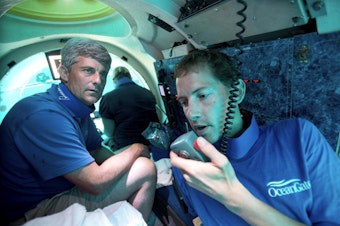 caption: Submersible pilot Randy Holt, right, communicates with the support boat as he and Stockton Rush, left, CEO and Co-Founder of OceanGate, dive in the company's submersible, "Antipodes," about three miles off the coast of Fort Lauderdale, Fla., June 28, 2013. 