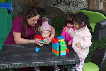 caption: Diana Llanes, owner and operator of Once Upon a Time Bilingual Childcare Center in Burien, plays with children outside on May 22, 2024 after the official launch of the campaign to defeat Initiative 2109. The initiative will appear on ballots in November and aims to repeal Washington's capital gains tax. The tax helps fund early learning and child care.