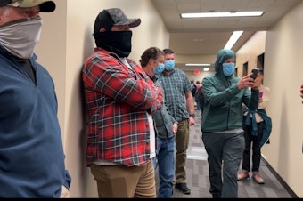 caption: Suspected agents with the U.S. Immigration and Customs Enforcement line the hallway outside a courtroom at the Seattle Immigration Court Wednesday.