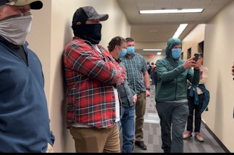 caption: Suspected agents with the U.S. Immigration and Customs Enforcement line the hallway outside a courtroom at the Seattle Immigration Court Wednesday.