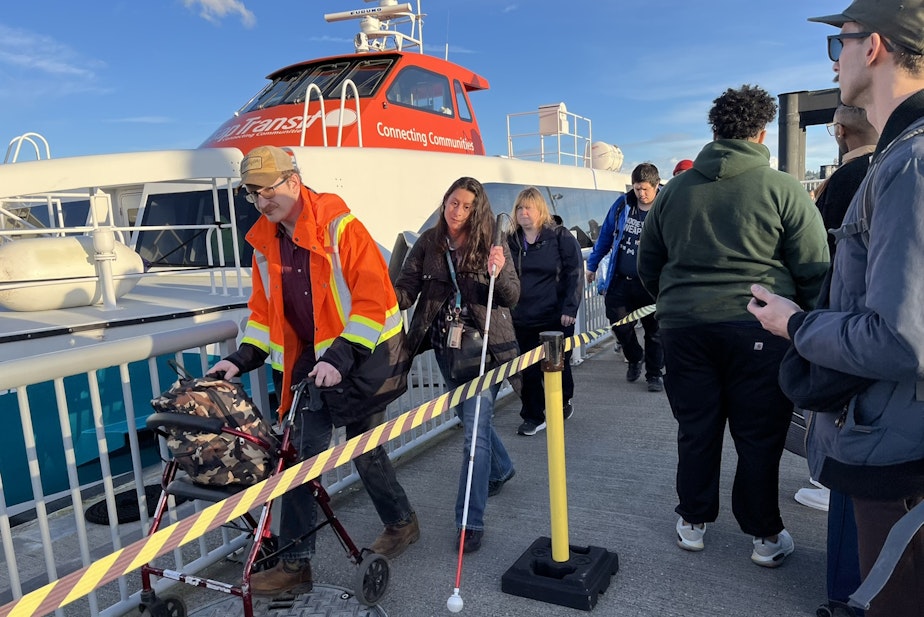 caption: Passengers disembarking from one of Kitsap Transit's passenger-only ferries while others wait to embark in February 2024.
