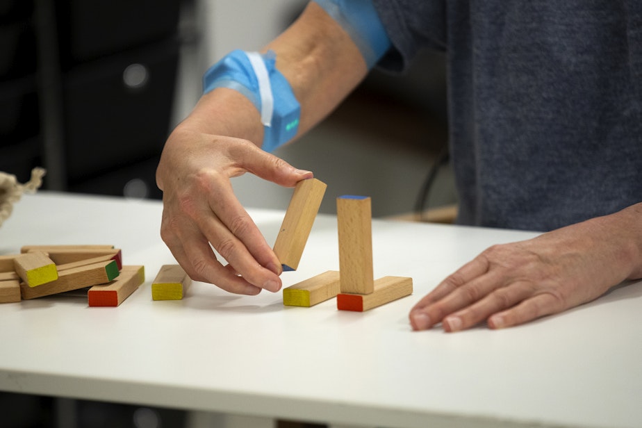 caption: Debbie Strom, a participant in a non-invasive transcutaneous spinal cord simulation session, stacks blocks on Monday, April 15, 2024, at Wallace Hall on the University of Washington campus in Seattle.