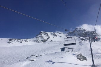 caption: Skiers wait in line for ski patrol to open up access to a ski area at the Whistler-Blackcomb ski resort in 2018.