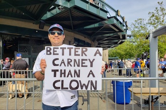 caption: A Toronto Blue Jays fan waives a sign that reads, "Better A Carney Than A Clown" in Seattle on Friday, May 9, 2025.