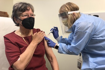 caption: As part of a phase 1 clinical trial of a variant-specific COVID-19 vaccine developed by Moderna, pharmacist Sue Lasicka gives a shot of the vaccine candidate to volunteer Suzanne Uvelli-Spencer, MD, on April 1, 2021, at Kaiser Permanente Washington Health Research Institute in Seattle.