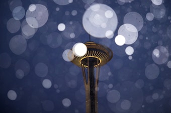 caption: Snow falls in front of the Space Needle on Sunday, Feb. 3, 2019, in Seattle.  Don't expect a similar dump this month, but lowland areas could still see some flakes.