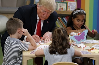caption: President Donald Trump writes in a coloring book during a visit with a group of children at the Nationwide Children's Hospital, Friday, Aug. 24, 2018, in Columbus, Ohio.