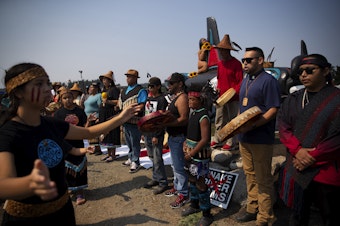 caption: Lummi tribal members including Chairman Anthony Hillaire, second from right, begin a celebration of life for Tokitae on Sunday, August 27, 2023, at Jackson Beach on San Juan Island. 