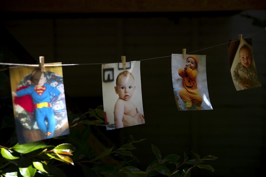 caption: Pictures of Arlo Philip hang from a string during his 1st birthday party on Saturday, May 29, 2021, at their home on Vashon Island.