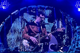 caption: Rivers Cuomo performs with Weezer on Oct. 4, 2024 at Seattle's Climate Pledge Arena as part of the Voyage to the Blue Planet tour. 