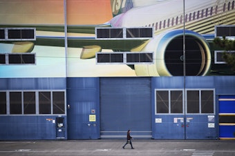 caption: A Boeing employee walks out of the Boeing Renton Factory after shift change on Monday, Dec. 16, 2019, in Renton.