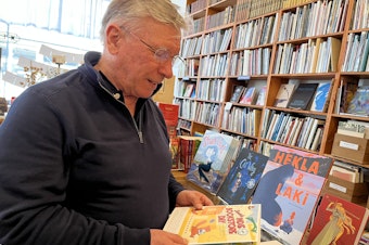 caption: Arundel Books founder Phil Bevis with this year's Seattle Indie Bookstore Day passport, also published in Pioneer Square across the street.