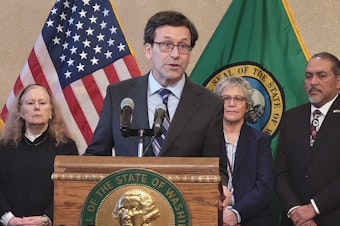 caption: Washington Gov. Bob Ferguson answered questions from reporters about his savings plans at a news conference Thursday, Feb. 27, 2025.