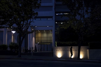 caption: A pedestrian walks in front of the King County Jail on Thursday, September 17, 2020, on Fifth Avenue in Seattle. 