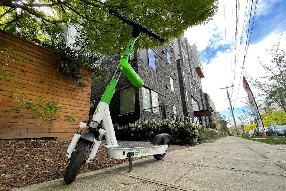 caption: A Lime scooter parked on a Northeast Seattle sidewalk.